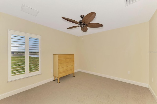 spare room featuring ceiling fan, light colored carpet, visible vents, and baseboards