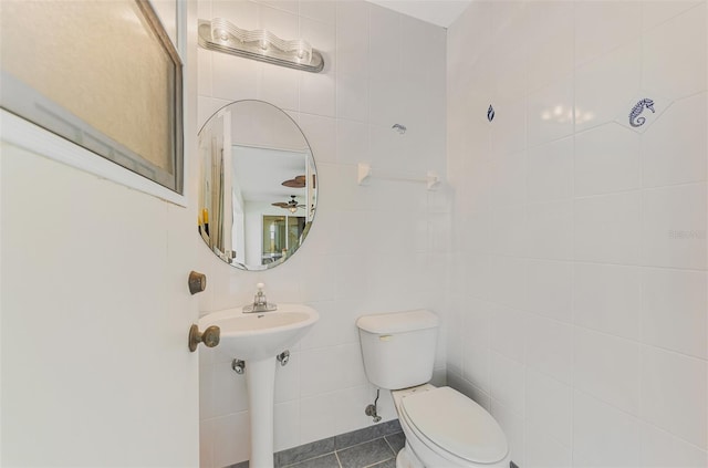 bathroom featuring tile walls, tile patterned floors, and toilet