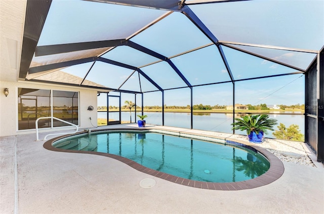 pool featuring glass enclosure, a patio area, and a water view