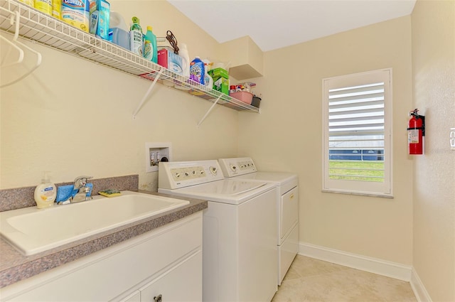 laundry room with washing machine and clothes dryer, light tile patterned floors, a sink, laundry area, and baseboards