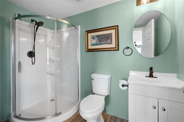 bathroom with hardwood / wood-style flooring, vanity, toilet, and walk in shower