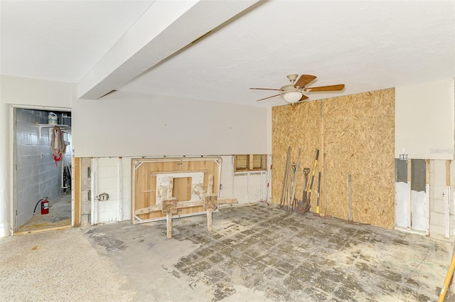 interior space featuring ceiling fan and concrete block wall