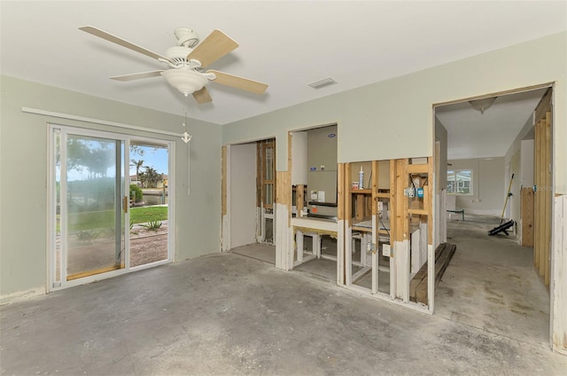 interior space with a ceiling fan, visible vents, and unfinished concrete floors