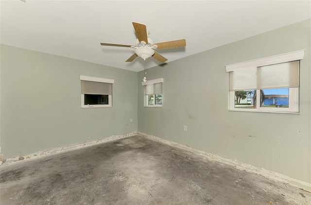 empty room with a ceiling fan and unfinished concrete flooring