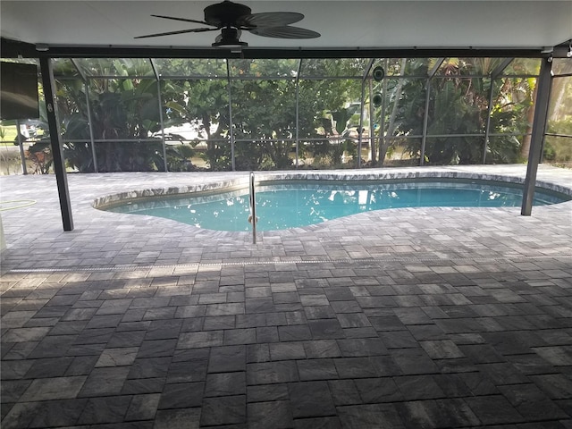 outdoor pool featuring glass enclosure, a patio area, and a ceiling fan