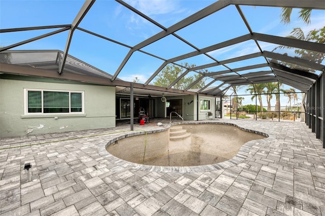 rear view of property featuring an empty pool, a patio area, glass enclosure, and stucco siding