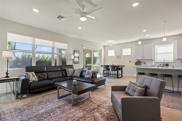 living room featuring ceiling fan and light hardwood / wood-style flooring