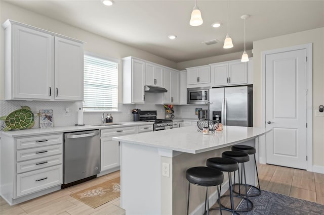 kitchen with sink, decorative light fixtures, a center island, stainless steel appliances, and white cabinets