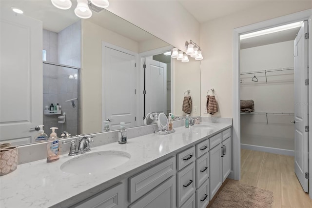 bathroom with an enclosed shower, vanity, and wood-type flooring