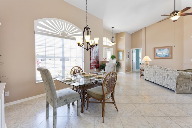 dining room with light tile patterned floors, ceiling fan with notable chandelier, and a high ceiling