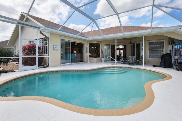 view of swimming pool featuring a patio area, ceiling fan, and glass enclosure