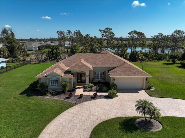 mediterranean / spanish home featuring a water view, a garage, and a front lawn