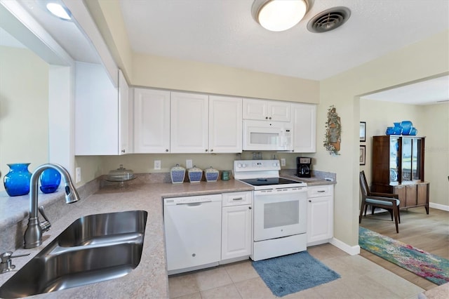 kitchen with sink, white appliances, white cabinets, and light tile patterned flooring