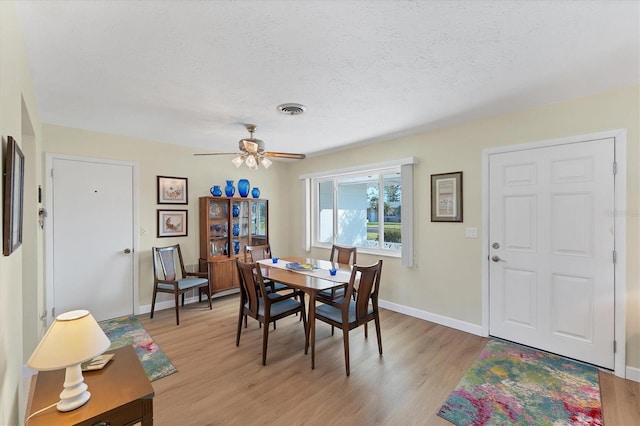 dining area with ceiling fan, light hardwood / wood-style flooring, and a textured ceiling