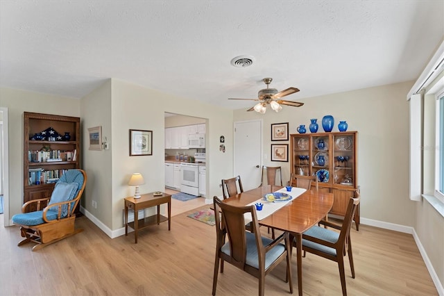 dining space with ceiling fan, a textured ceiling, and light wood-type flooring