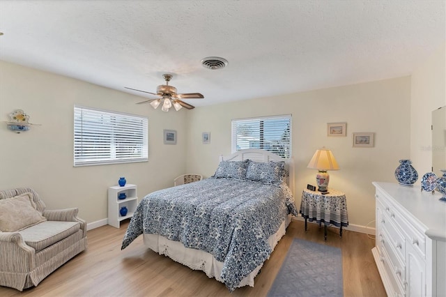 bedroom with ceiling fan, a textured ceiling, and light hardwood / wood-style floors