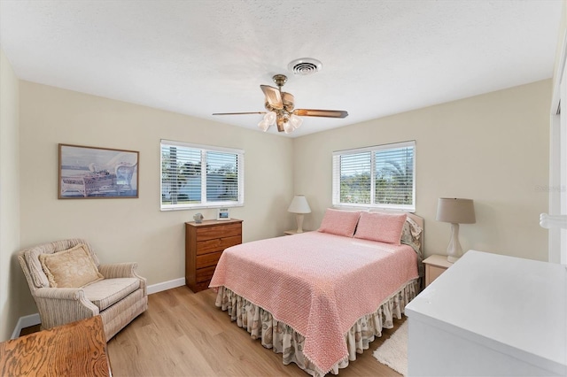 bedroom featuring ceiling fan, a textured ceiling, and light wood-type flooring