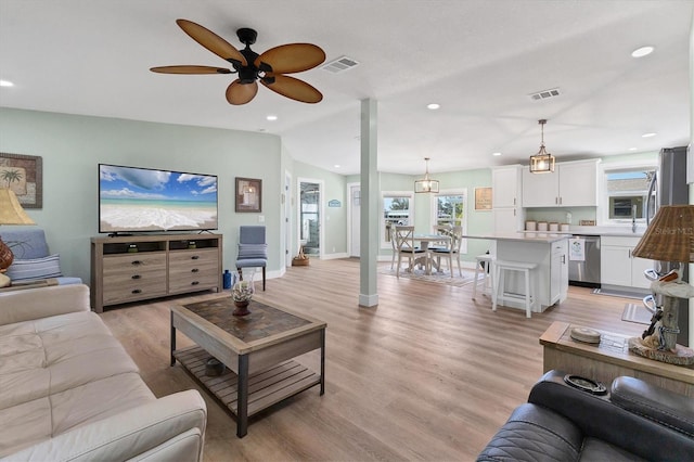 living room with ceiling fan, lofted ceiling, and light wood-type flooring