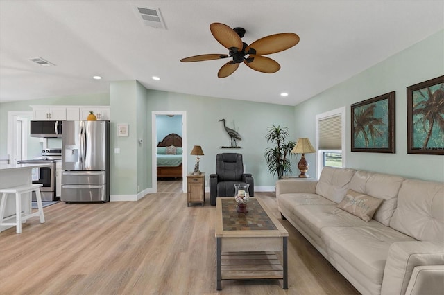 living room with vaulted ceiling, ceiling fan, and light wood-type flooring