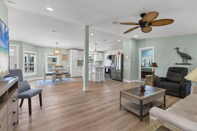 living room with ceiling fan, lofted ceiling, and light hardwood / wood-style floors