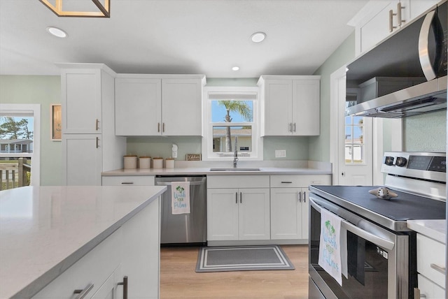 kitchen with sink, light hardwood / wood-style flooring, stainless steel appliances, and white cabinets