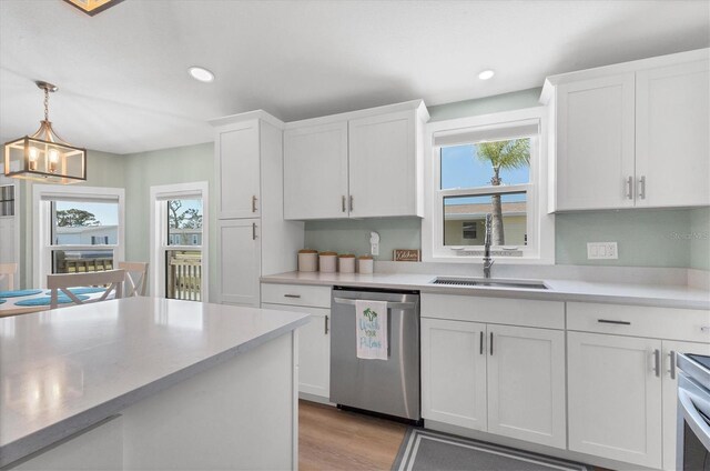 kitchen with pendant lighting, sink, dishwasher, light hardwood / wood-style floors, and white cabinets