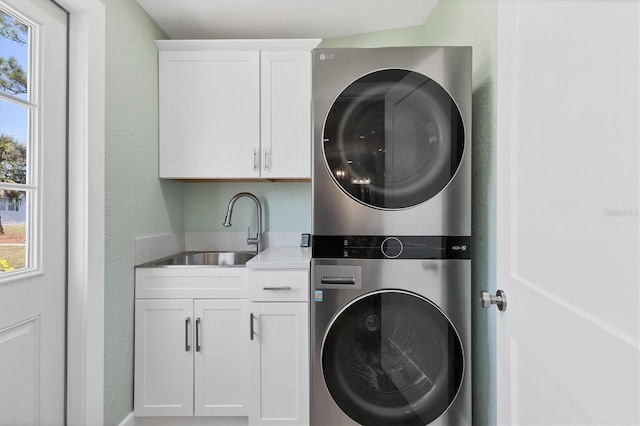 laundry area featuring sink, cabinets, and stacked washer / dryer