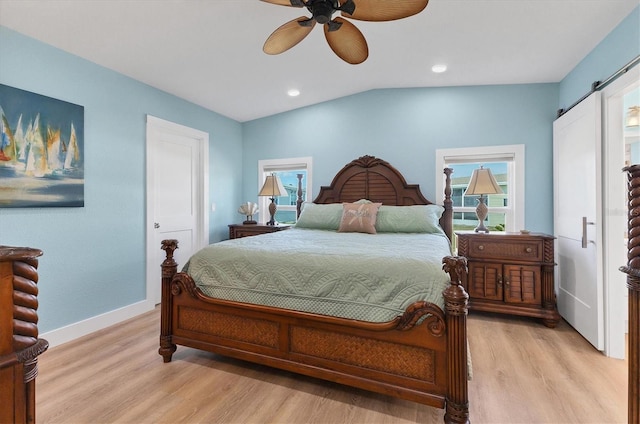 bedroom with ceiling fan, a barn door, and light hardwood / wood-style floors