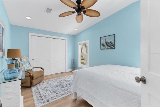 bedroom with vaulted ceiling, hardwood / wood-style floors, ceiling fan, and a closet