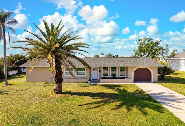 ranch-style house featuring a shingled roof, concrete driveway, a front yard, stucco siding, and a garage