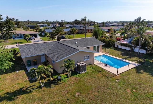 view of swimming pool featuring a fenced in pool, a lawn, a residential view, and central AC