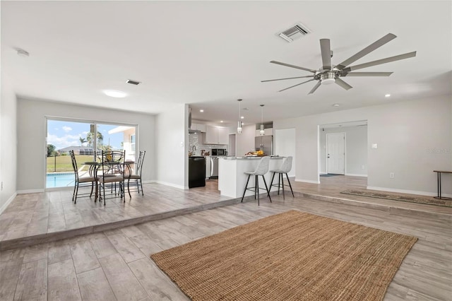 unfurnished living room featuring ceiling fan and light wood-type flooring