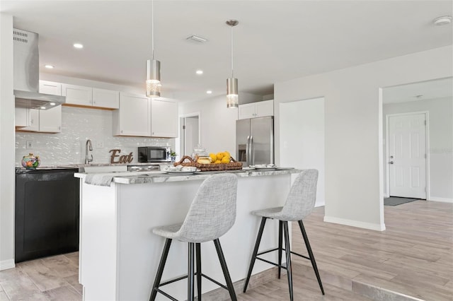 kitchen with hanging light fixtures, island exhaust hood, stainless steel refrigerator with ice dispenser, white cabinets, and a kitchen island