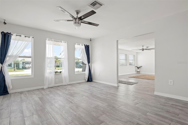 empty room featuring light hardwood / wood-style flooring, ceiling fan, and plenty of natural light