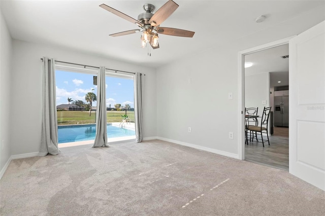 empty room with ceiling fan and light carpet