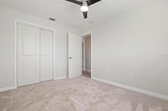 unfurnished bedroom featuring light carpet, ceiling fan, and a closet