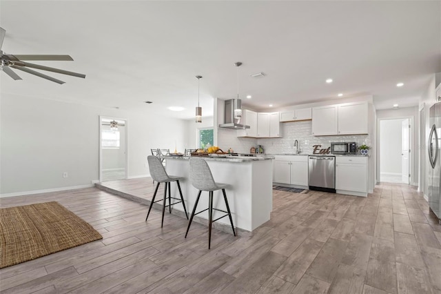 84 Caddy Rd, Rotonda West, FL 33947 - kitchen featuring stainless steel appliances, wall chimney exhaust hood, light wood-style floors, a ceiling fan, and backsplash