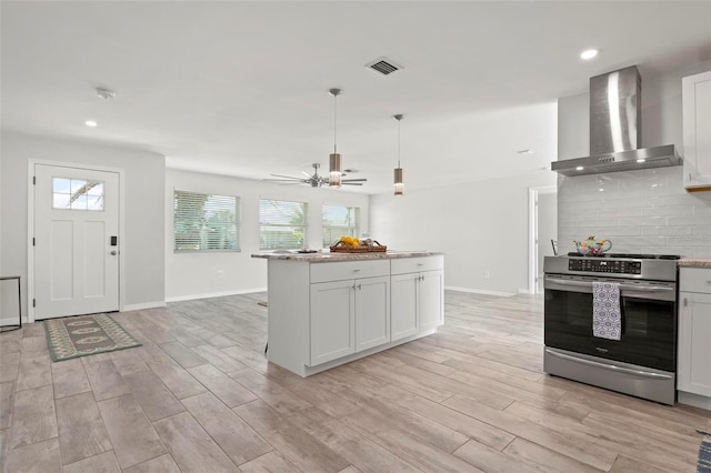 84 Caddy Rd, Rotonda West, FL 33947 - kitchen featuring wall chimney range hood, stainless steel electric range, decorative backsplash, light wood-style floors, and ceiling fan