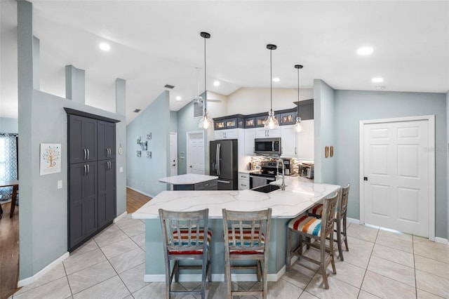 kitchen featuring sink, a breakfast bar, appliances with stainless steel finishes, decorative light fixtures, and kitchen peninsula