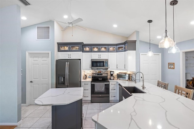 kitchen with sink, a breakfast bar area, light stone counters, decorative light fixtures, and appliances with stainless steel finishes