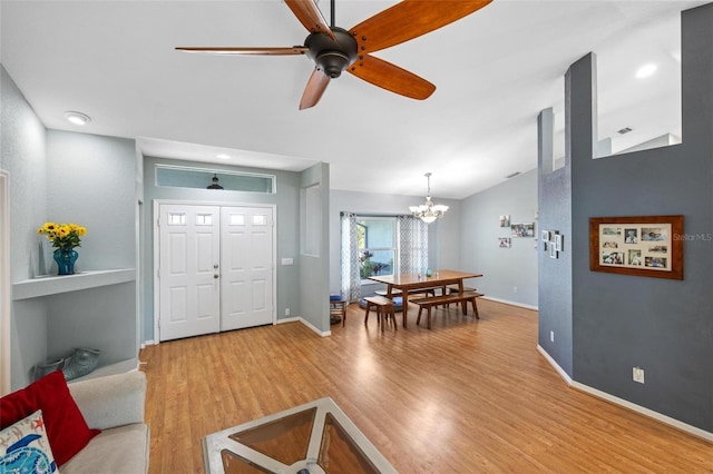 living room with lofted ceiling, ceiling fan with notable chandelier, and wood-type flooring