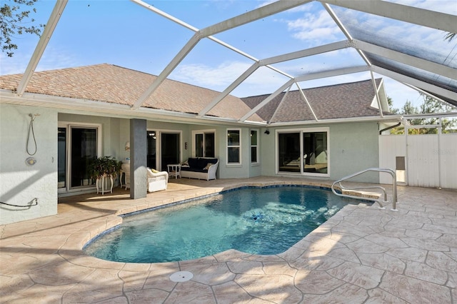 view of pool with outdoor lounge area, glass enclosure, and a patio area