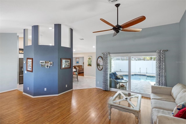 living room featuring ceiling fan, high vaulted ceiling, and light wood-type flooring