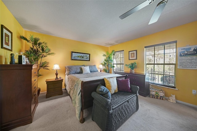 bedroom featuring a textured ceiling, light colored carpet, and ceiling fan