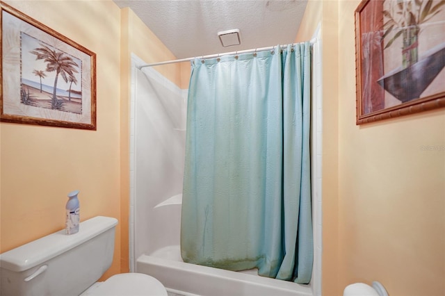 bathroom featuring shower / tub combo with curtain, a textured ceiling, and toilet