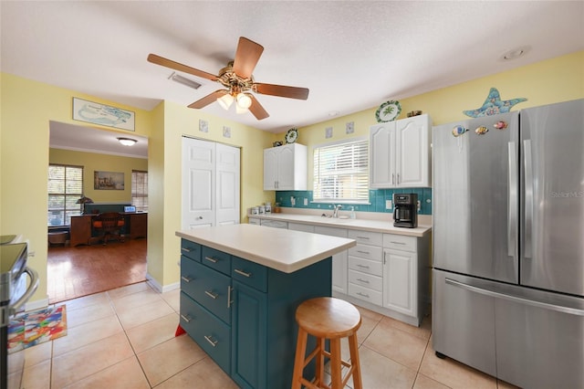 kitchen with white cabinetry, light tile patterned floors, stainless steel refrigerator, and a center island