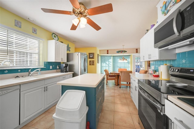 kitchen featuring sink, white cabinetry, appliances with stainless steel finishes, a kitchen island, and pendant lighting