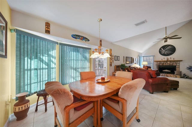 tiled dining area with a stone fireplace, lofted ceiling, and ceiling fan