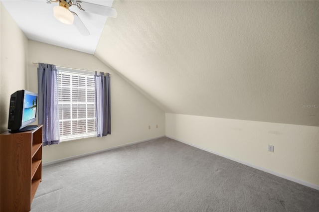 additional living space featuring ceiling fan, light colored carpet, lofted ceiling, and a textured ceiling