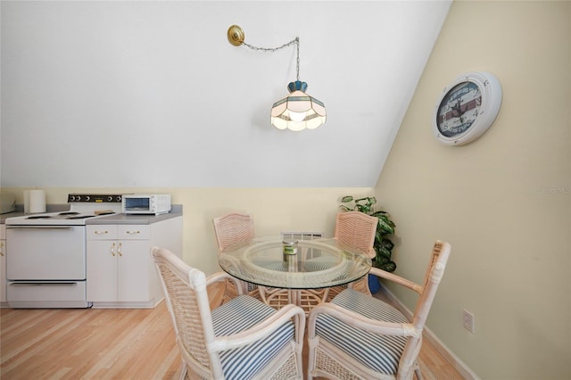 dining area with light hardwood / wood-style flooring and vaulted ceiling